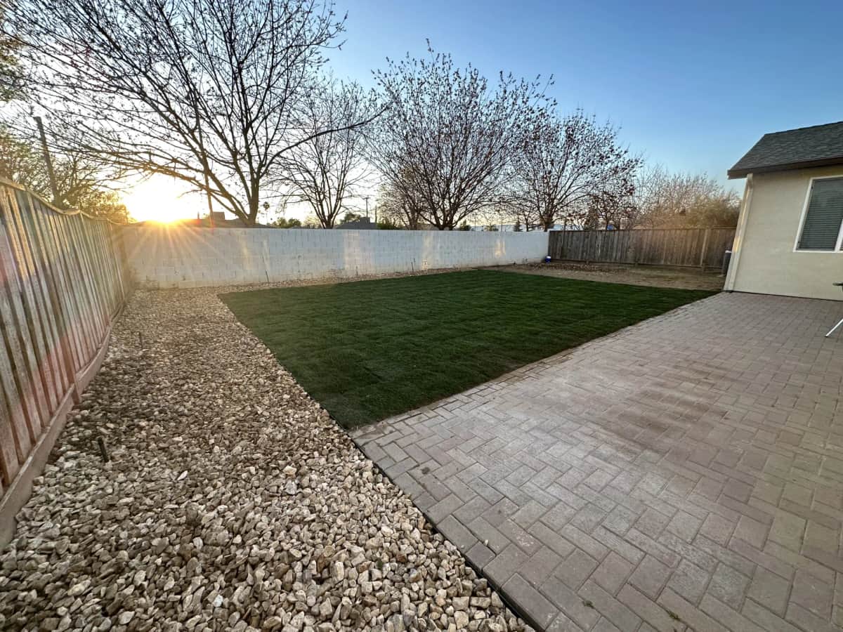 Backyard paver patio with river rock border