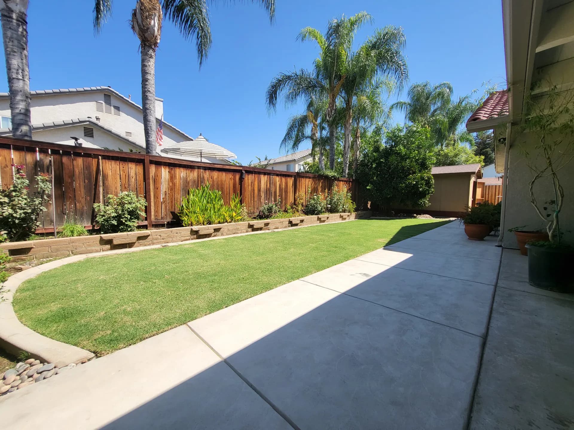 Wide view of sod backyard with retaining wall