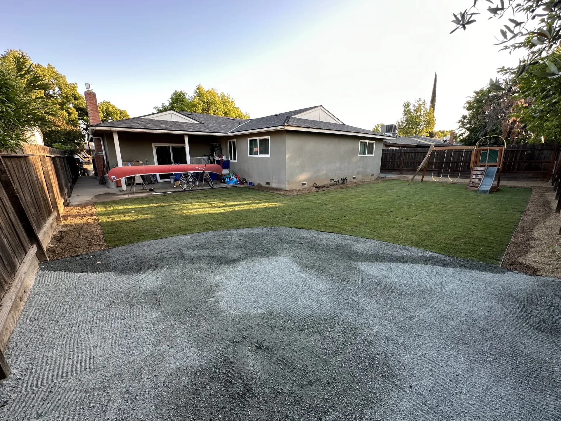 Large backyard sod installation in progress with gravel area