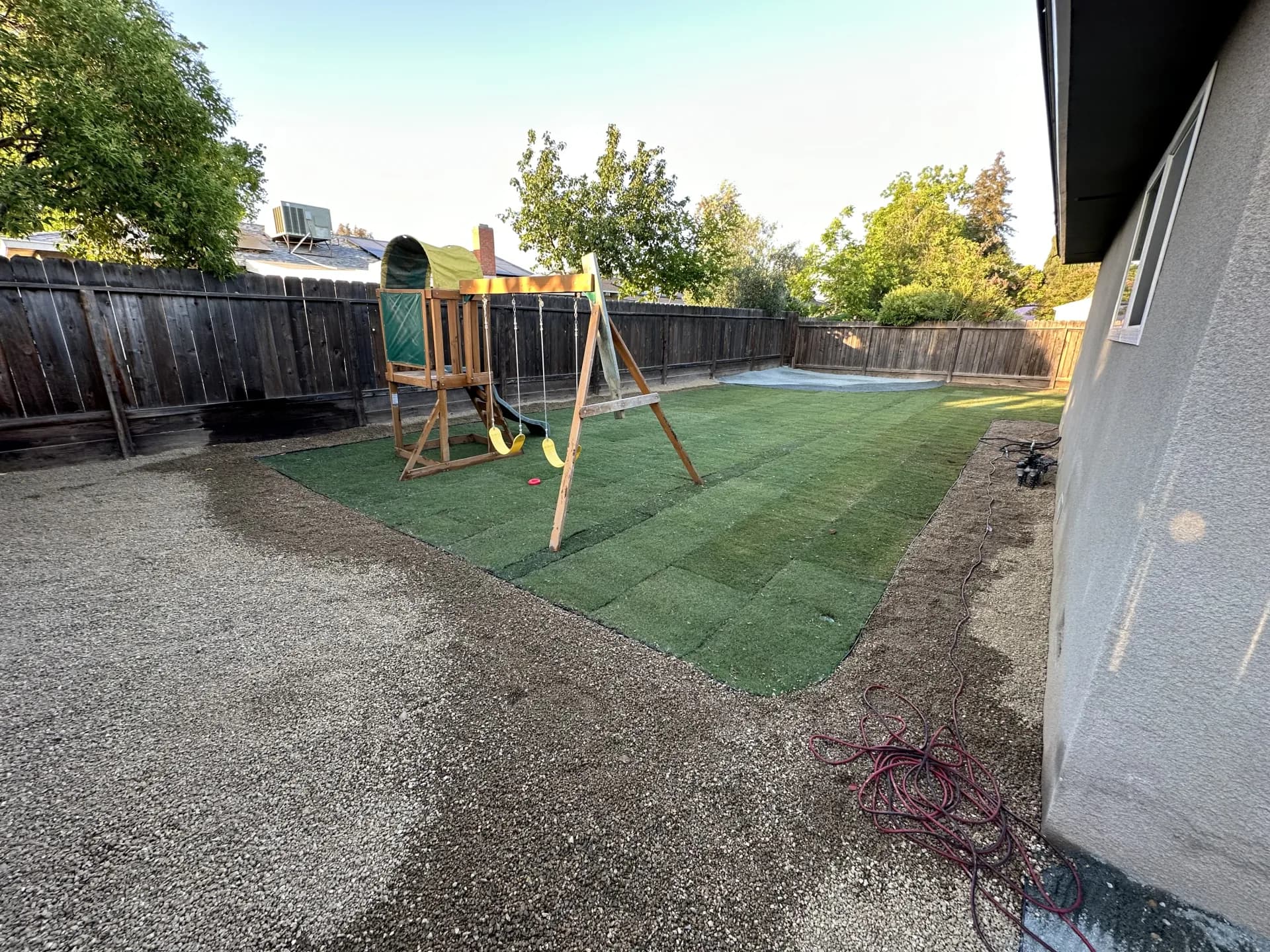 Large sod backyard with playset and gravel area